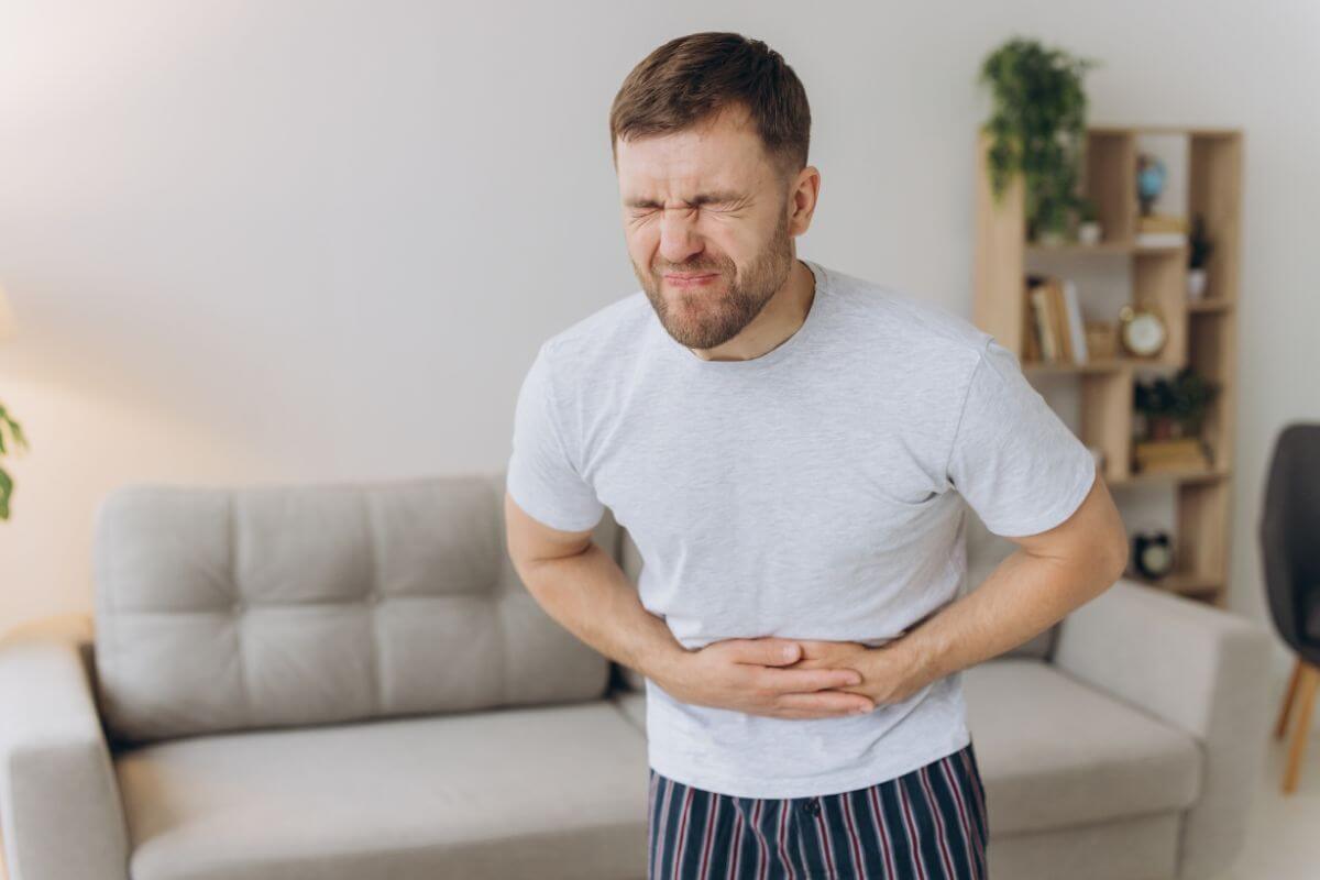 Mann hält sich den Bauch vor Schmerzen – nervöser Magen als körperliche Folge von Angst und innerer Anspannung