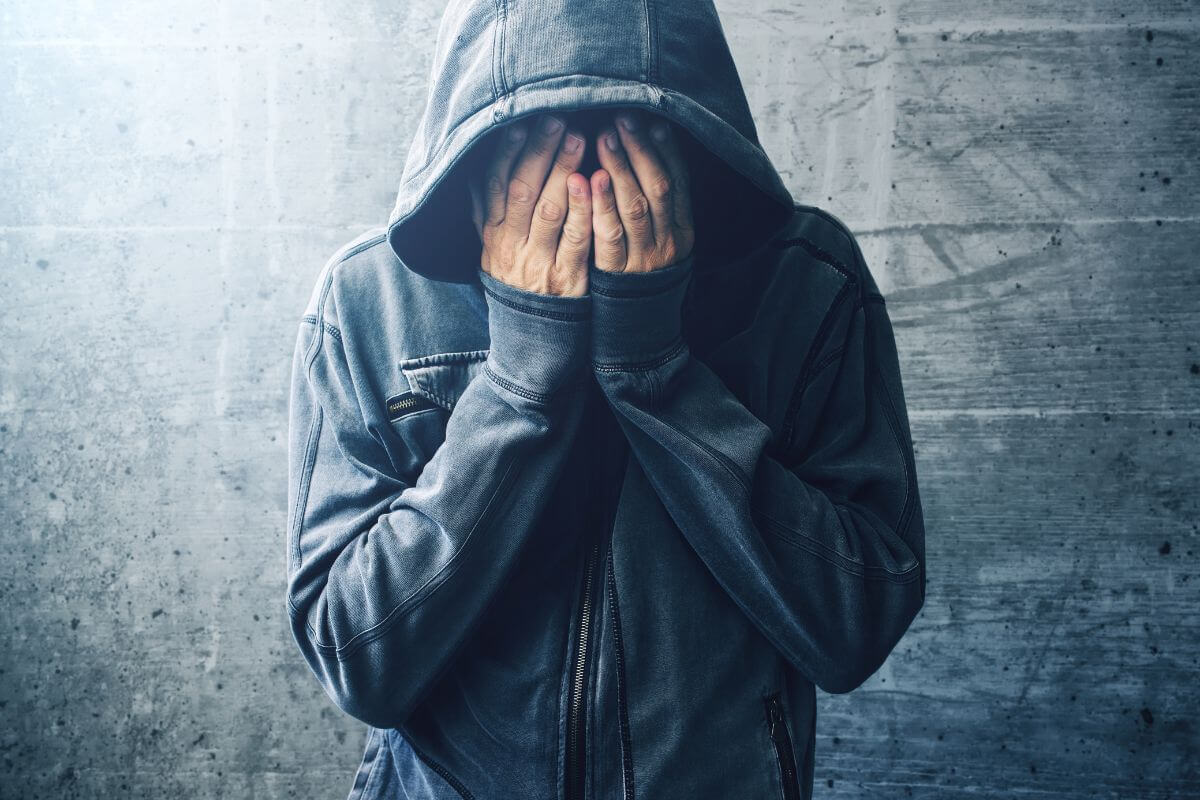 Junge Frau schaut nachdenklich aus dem Fenster an einem Regentag – ein Symbol für sozialen Rückzug, Überforderung und das Bedürfnis nach innerer Ruhe.